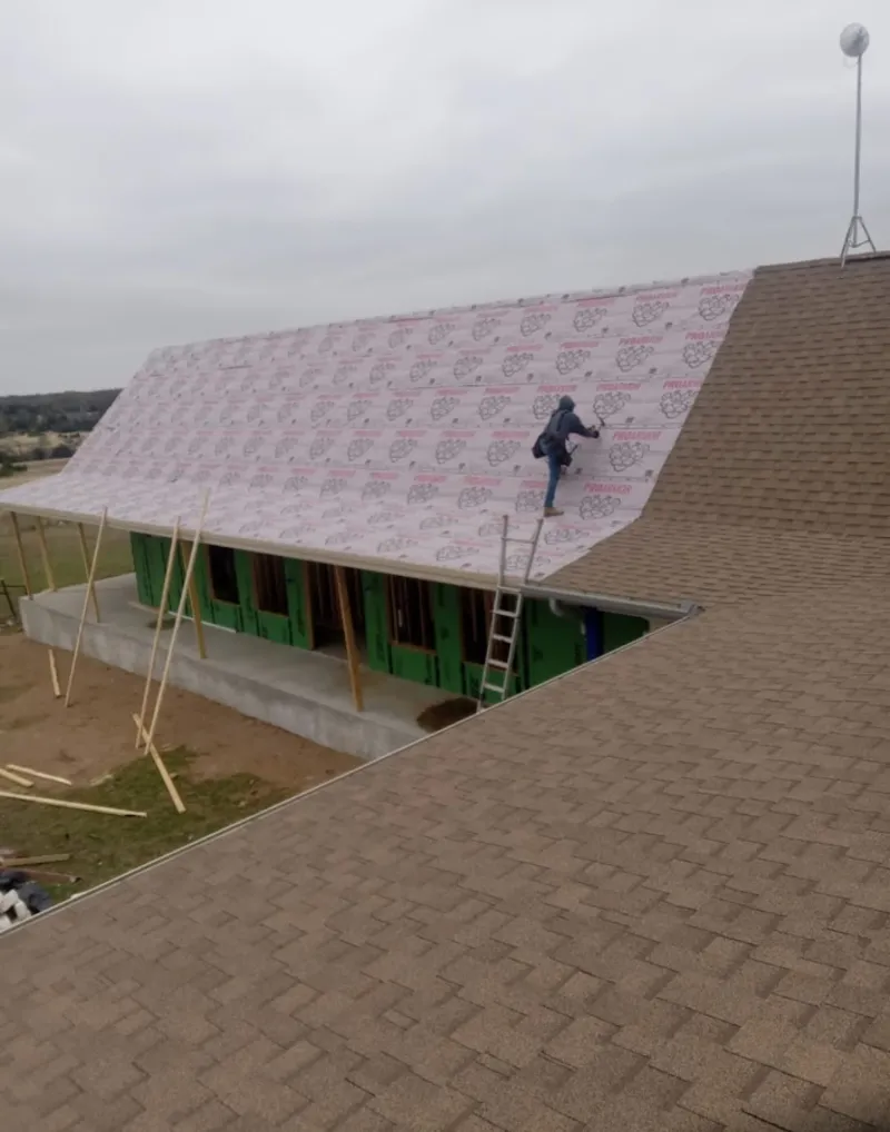 Worker preparing underlayment for a metal roof installation in Warren